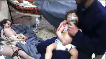  ?? — AFP photo ?? File image grab taken from a video released by the Syrian civil defence in Douma shows unidentifi­ed volunteers giving aid to children at a hospital following an alleged chemical attack on the rebel-held town.