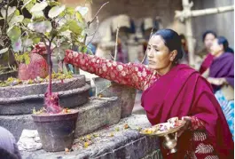  ?? ?? Devotion is part of everyday life in Nepal: A local woman places an offering of floral petals in a holy shrine.