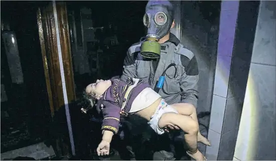  ?? AP ?? Un miembro de la Fuerza de Defensa Civil siria sostiene el cuerpo de un niño tras el ataque químico del sábado