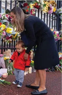  ?? ?? All ages pay their respects: A youngster amid the floral tributes, while a man appears overcome