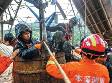  ?? PAN YULONG / XINHUA ?? Rescued miners are lifted to safety at an iron ore mine in Benxi, Liaoning province, on Wednesday. A total of 23 trapped miners have been rescued and two others are unaccounte­d for after a blast at 4:10 pm on Tuesday.