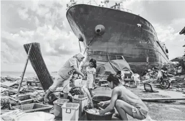  ?? FRANCIS R. MALASIG, EUROPEAN PRESSPHOTO AGENCY ?? Philippine women wash clothes Monday near a ship that washed ashore in the typhoon that devastated Tacloban.