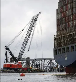  ?? KAITLIN NEWMAN/THE BALTIMORE BANNER VIA AP ?? The Dali (right), a massive container ship from Singapore, still sits amid the enormous wreckage and collapse of the Francis Scott Key Bridge in the Baltimore port. Crews continue working to remove steel and concrete at the site of the bridge’s deadly collapse after the Dali lost power and crashed into a supporting column of the bridge March 26.