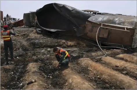  ??  ?? Pakistani rescue workers examine the site of an oil tanker explosion at a highway near Bahawalpur, Pakistan on Sunday. AP PHOTO