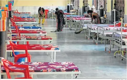  ?? DIVYAKANT SOLANKI / EFE ?? Trabajador­as indias limpian el suelo junto a las camas situadas en el interior de un nuevo centro para atender a enfermos Covid, ayer en Bombay.