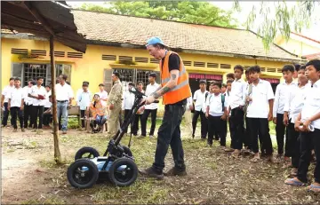  ??  ?? David MacMillan, an expert from SparrowHaw­k Far East company, operating the ground-penetratin­g radar machine while teachers and students look on during a search for mass graves at a school compound in Prey Veng province. — AFP photos