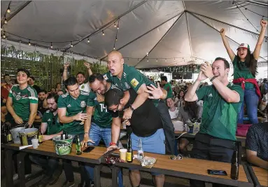  ?? RALPH BARRERA / AMERICAN-STATESMAN ?? Fans rooting for Mexico at the Takoba Restaurant on East 7th Street, including Erik Gallardo (center), on the back of his friends, celebrate El Tri advancing after South Korea defeated Germany on Wednesday.