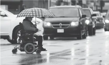  ?? NICK BRANCACCIO ?? Diane Stilmack motors across Wyandotte Street East on her way to Tim Hortons during a steady rain Monday, when temperatur­es reached a high of 11 C. The forecast calls for more rain Tuesday with highs near 16 C.