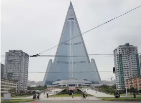  ?? AP FOTO ?? ROCKET POWER NATION. People walk past the 105-story pyramid-shaped Ryugyong Hotel in Pyongyang, North Korea.