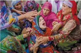 ?? — AP ?? Ruksana Nazir, center, is comforted during the funeral of her husband Nazir Ahmed Wani in Srinagar. Suspected rebels on Friday shot and killed two activists, which included Wani of National conference.