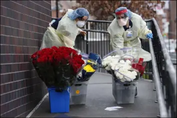  ?? Kathy Willens The Associated Press ?? Nurses take donated flowers Saturday up a ramp outside Elmhurst Hospital Center’s emergency room in New York.