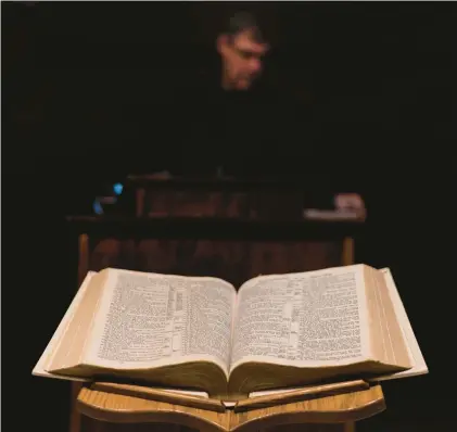  ?? DAVID GOLDMAN/AP PHOTOS ?? A Bible sits open as Pastor Rick Mannon stands at the pulpit at Calvary Assembly of God on Nov. 16 in Wilson, Wis.