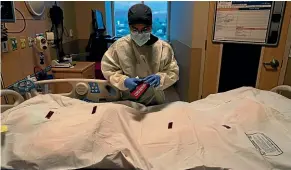  ?? AP ?? Los Angles nurse Bryan Hofilena attaches a ‘‘Covid patient’’ sticker on a body bag. The United States could reach a million deaths from the pandemic by April.