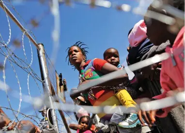  ?? PICTURE: EPA ?? SUCCOUR: Mothers and children queue for food at a Red Cross refugee camp set up for foreign residents in April because of xenophobic attacks in Primrose, near Johannesbu­rg.