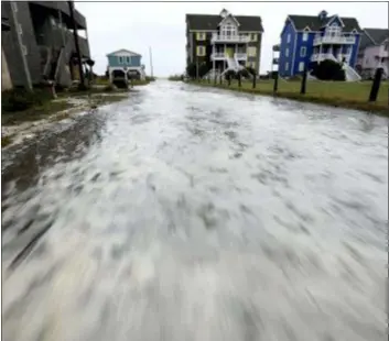  ?? STEVE EARLEY — THE VIRGINIAN-PILOT VIA AP ?? Ocean water rushes down Cape Hatteras Pier Drive in Frisco, N.C., on Hatteras Island as the effects of Hurricane Florence reach the area on Thursday.