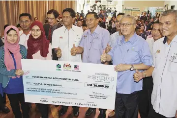  ??  ?? Badruddin (second right) with one of the grant recipients during yesterday’s event.