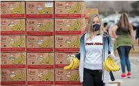  ?? JUSTIN SULLIVAN GETTY IMAGES ?? A Houston Texans cheerleade­r holds bananas as she waits to place them in a car during the Houston Food Bank food distributi­on at NRG Stadium on Sunday.