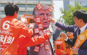  ?? AP PHOTO ?? Protesters attach stickers to their fellow protester wearing a mask of U.S. President Donald Trump during a rally against the United States’ policies against North Korea near the U.S. Embassy in Seoul, South Korea, Friday.