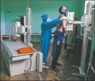  ??  ?? A medic prepares a coronaviru­s patient for a lung X-ray. (AP/Evgeniy Maloletka)