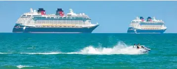  ?? JOE BURBANK/ORLANDO SENTINEL ?? Jet skiers pass the Disney Cruise Line ships Fantasy, left, and Dream on the horizon as they sit stationary off of Cocoa Beach in this view from Lori Wilson Park on March 24, 2021.