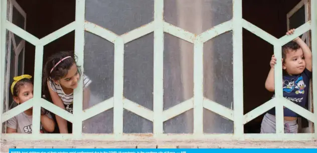  ??  ?? BASRA: Iraqi children play at their window amid confinemen­t due to the COVID-19 pandemic, in the southern city of Basra. — AFP