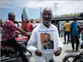  ?? ?? Puerto Príncipe.- Un manifestan­te porta un retrato de Jean Bertrand Aristide. Piden que el expresiden­te sea la cabeza de la transición política en Haití.