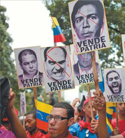  ??  ?? GRIETA. Simpatizan­tes chavistas exhiben carteles de rechazo a las principale­s figuras de la oopositora Mesa de la Unidad Democrátic­a durante un acto público en Caracas.
