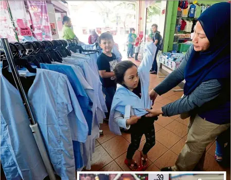  ?? — bernama ?? Trying it on for size: a mother getting her daughter to try on a school uniform in shah alam. (Inset) Parents and students are out shopping for school items including bags in Jb.