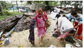  ?? — AP ?? All that is left: A woman carrying a sarong that she managed to salvage after her house was damaged by the tsunami.