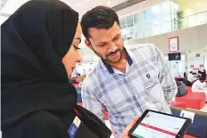  ?? Arshad Ali/Gulf News ?? RTA staff helping a customer about online services at the ■ Customer Service Centre in Umm Ramool.