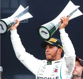  ??  ?? Mercedes driver Lewis Hamilton, of Britain, raises trophies after winning the Brazilian Formula One Grand Prix at the Interlagos race track Photo: AP