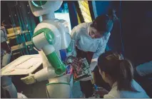  ??  ?? Waitresses repair a robot at Robot Magic Restaurant in Shanghai. Servers at the diner said their automated counterpar­ts caused more work than they saved, since the robots cannot actually place plates of food onto a table and they regularly break down.