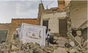  ?? (AFP) ?? Two boys hold a poster welcoming Pope Francis above the rubble of a destroyed house, in Iraq’s northern city of Mosul on Tuesday