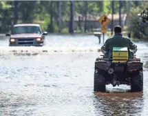  ?? SEAN RAYFORD, GETTY IMAGES ?? A man navigates a flooded street on a four-wheeler in the Browns Ferry community near Georgetown, S.C.