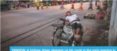  ??  ?? YANGON: A trishaw driver sleeping on his cycle in the early evening in Yangon.—AFP