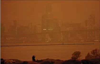  ?? JANE TYSKA — STAFF ARCHIVES ?? A person takes a photo of the San Francisco skyline with their phone from Middle Harbor Shoreline Park in Oakland on Sept. 9, 2020. The unusual orange and red-hued skies were a result of smoke from the Northern California wildfires.