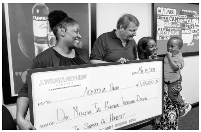  ?? CONTRIBUTE­D ?? J. Wray & Nephew Limited Managing Director Jean-Philippe Beyer (second left) and Tanikie McClarthy Allen (left), director, Public Affairs and Sustainabi­lity, make a presentati­on of $1.2 million for honesty to Ackaisha Green, while she holds her son Joshua, at JWN’s corporate offices in New Kingston on Tuesday.