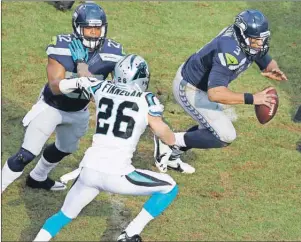  ?? AP PHOTO ?? Seattle Seahawks quarterbac­k Russell Wilson (3) runs by Carolina Panthers defensive back Cortland Finnegan (26) during the second half of an NFL divisional playoff game, Sunday in Charlotte, N.C.