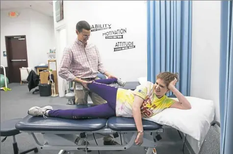  ?? Stephanie Strasburg/Post-Gazette photos ?? Physical therapist Jeff Faulring of Greenfield, works with author Jenevieve Woods, 20, during her session at Orthopedic & Sports Physical Therapy Associates on Monday in Ross. Ms. Woods goes to physical therapy twice a week because of the effects of...