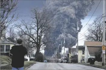  ?? GENE J. PUSKAR/AP ?? A MAN TAKES PHOTOS AS A BLACK PLUME RISES over East Palestine, Ohio, as a result of a controlled detonation of a portion of the derailed Norfolk Southern train on Monday.