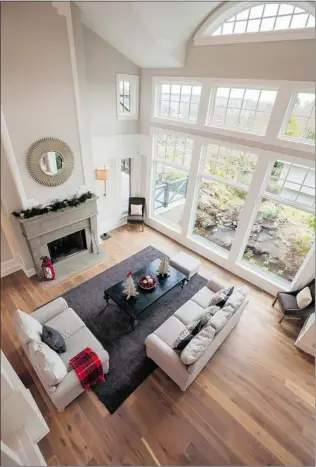  ??  ?? The living room, right, which overlooks the waterfront, has a half- moon window high up toward the ceiling. It matches a similar half moon over the entry at the front of the house. The dining area, bottom left, features water views through the trees,...