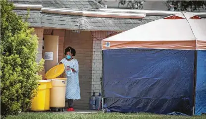  ?? Photos by Steve Gonzales / Staff photograph­er ?? A woman wearing personal protective equipment disposes of a bag Thursday at Windsong Care Center in Pearland.