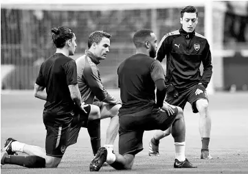  ?? — AFP photo ?? Arsenal’s German midfielder Mesut Ozil (right) warms up before the UEFA Europa League semi-final second leg football match between Club Atletico de Madrid and Arsenal FC.