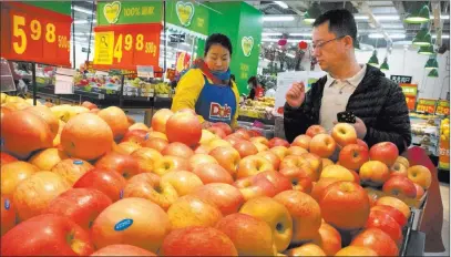  ?? Mark Schiefelbe­in ?? The Associated Press file A woman wearing a uniform with the logo of an American produce company helps a customer shop at a supermarke­t in
Beijing. China raised import duties on U.S. pork, fruit and other products Monday in an escalating tariff...