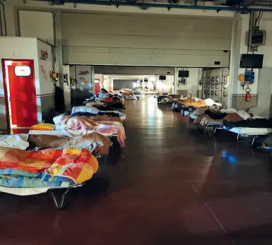  ??  ?? Sopra madre e figlia sfollate si tengono la mano prima di addormenta­rsi nella palestra comunale di Barberino allestita per l’emergenza A sinistra altri sfollati nel paddock dell’Autodromo A destra i volontari della Misericord­ia Francesco Santangeli e Adriano Lucchesi