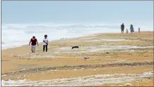  ?? GERRY BROOME/AP PHOTO ?? People walk the beach in Kill Devil Hills, N.C., Sept. 13 as Hurricane Florence approached the East Coast.