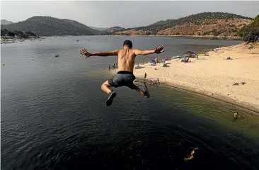  ?? GETTY IMAGES ?? A young man cools off at Madrid’s San Juan Reservoir during the scorching summer that gripped Europe this year. The warmth has continued into winter, with temperatur­es 15C to 20C above normal expected across the heart of the continent this week.