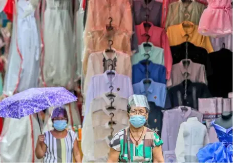  ?? ROUELLE UMALI/XINHUA ?? Stolen moment Elder persons sporting protective gear visit a street clothes shop despite the strict government regulation on individual­s 60 and above to stay home. More than one year of lockdowns have worn out the patience of Filipinos who largely loves the outdoor.