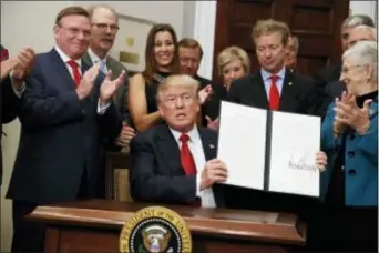  ?? EVAN VUCCI — THE ASSOCIATED PRESS FILE ?? In this photo, President Donald Trump shows an executive order on health care that he signed in the Roosevelt Room of the White House, in Washington. Trump presented a distorted picture of his tax plan this past week and claimed he was trying to keep...