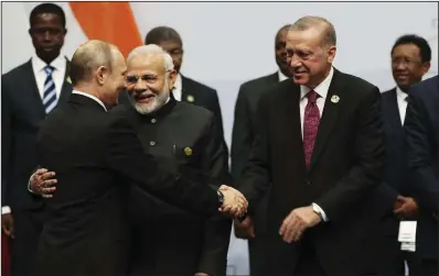  ?? AP ?? Russian President Vladimir Putin greets President Recep Tayyip Erdogan of Turkey before they pose with other leaders Friday at the emerging national economies summit in Johannesbu­rg. Putin said at the gathering that he was prepared to visit President Donald Trump in Washington and that Trump is welcome to visit Moscow, an invitation that Trump indicated he was willing to accept.